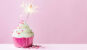 pink cupcake with sparker for candle on a pink background
