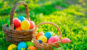 two easter baskets overflowing with easter eggs in grass