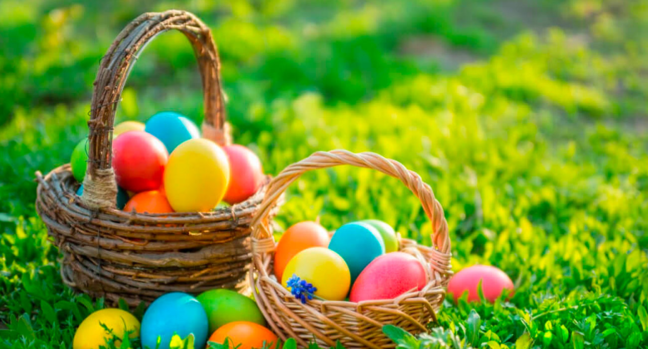 two easter baskets overflowing with easter eggs in grass