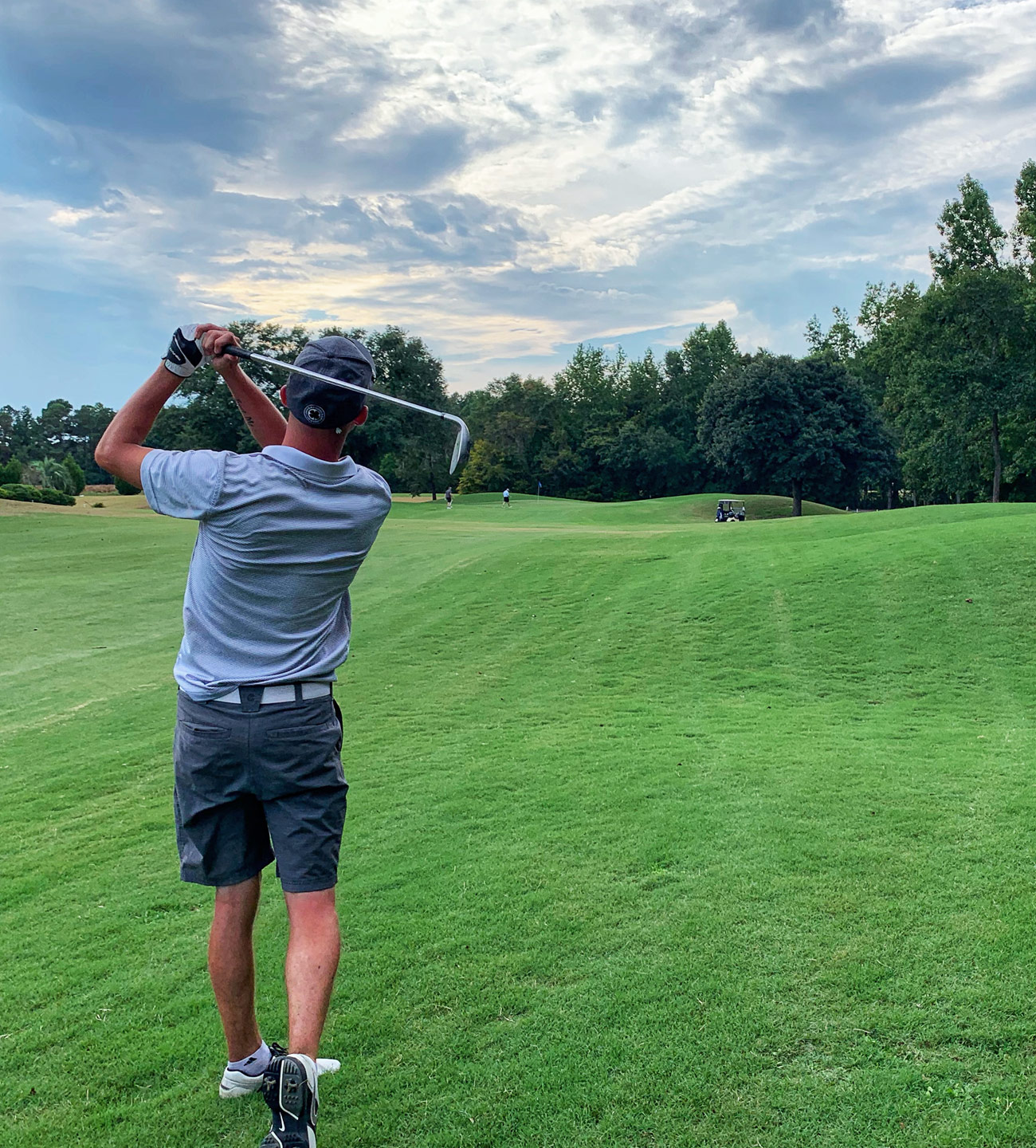 man post golf swing on fairway