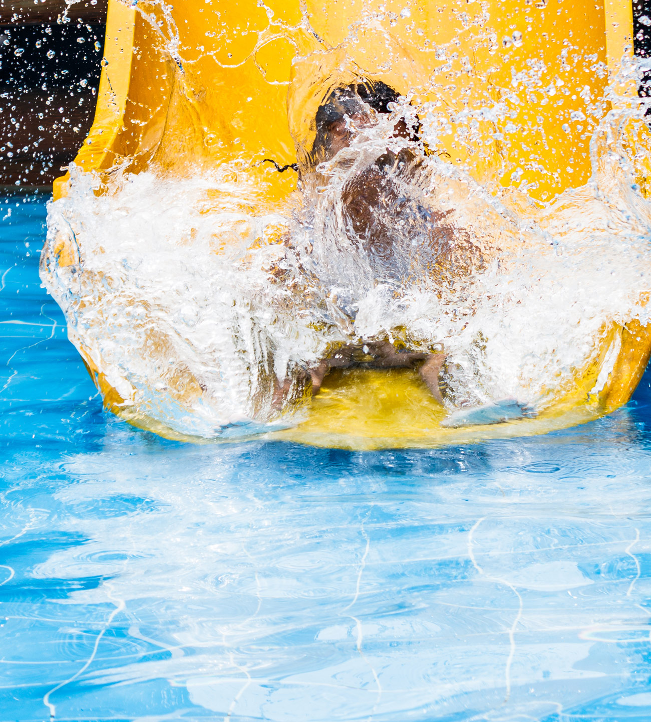 child splashing into pool from water slide