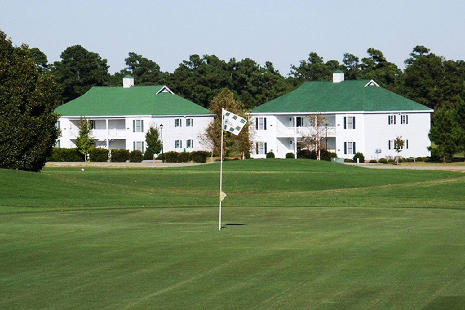 white villas with green roofs with golf course in front